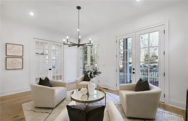 sitting room featuring an inviting chandelier, french doors, and light hardwood / wood-style flooring