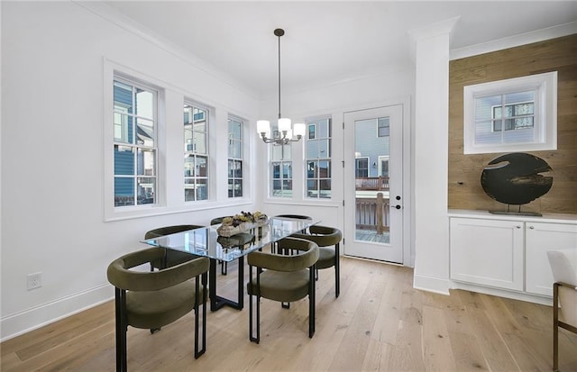 dining room featuring ornamental molding, light wood-type flooring, and a notable chandelier