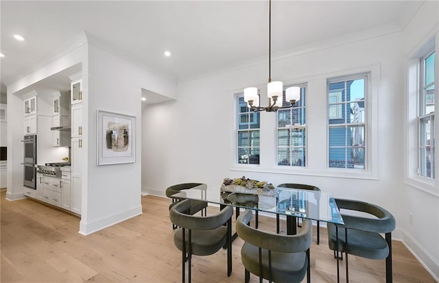 dining space with crown molding, an inviting chandelier, and light hardwood / wood-style flooring