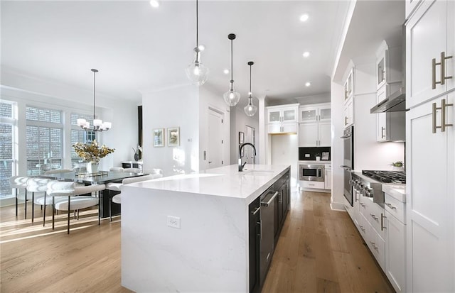 kitchen featuring sink, white cabinets, an island with sink, and decorative light fixtures