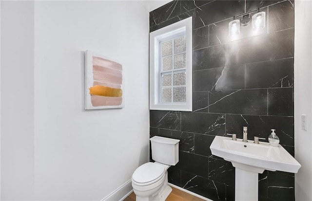 bathroom featuring toilet, decorative backsplash, tile walls, and sink