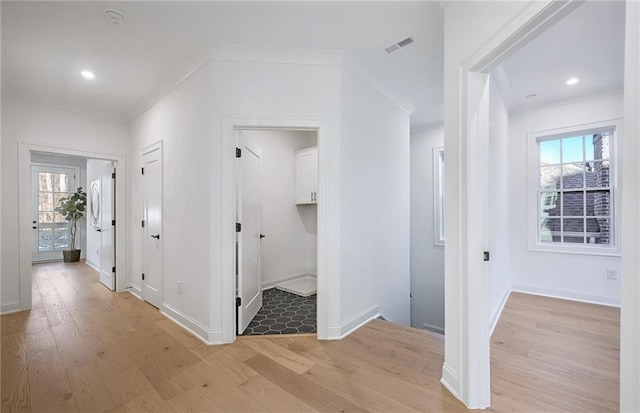 corridor featuring light wood-type flooring, a healthy amount of sunlight, and ornamental molding