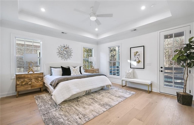 bedroom with a raised ceiling, ceiling fan, light hardwood / wood-style flooring, and access to exterior