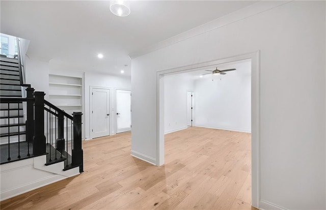 hall featuring built in shelves, crown molding, and light hardwood / wood-style flooring