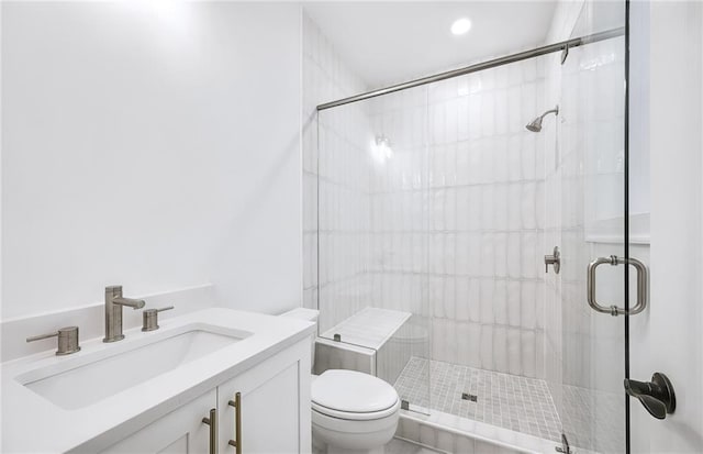 bathroom with toilet, vanity, and a shower with shower door