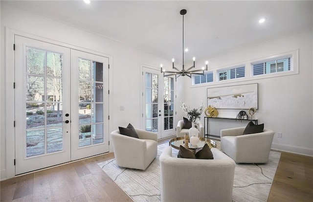 living room featuring french doors, a chandelier, and light wood-type flooring