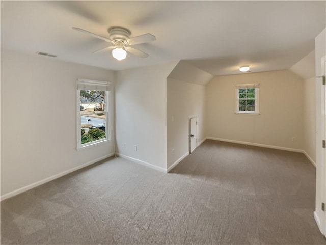 additional living space featuring carpet floors, plenty of natural light, visible vents, and baseboards