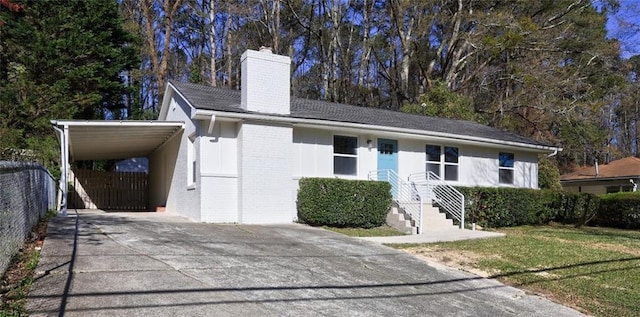 ranch-style home with driveway, a carport, fence, brick siding, and a chimney