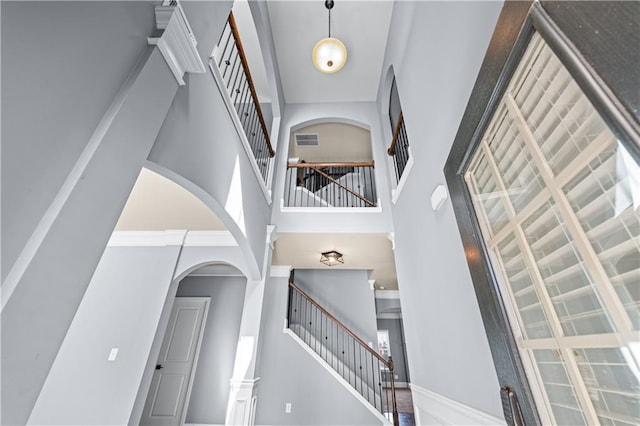 foyer entrance featuring a high ceiling, visible vents, baseboards, stairway, and crown molding