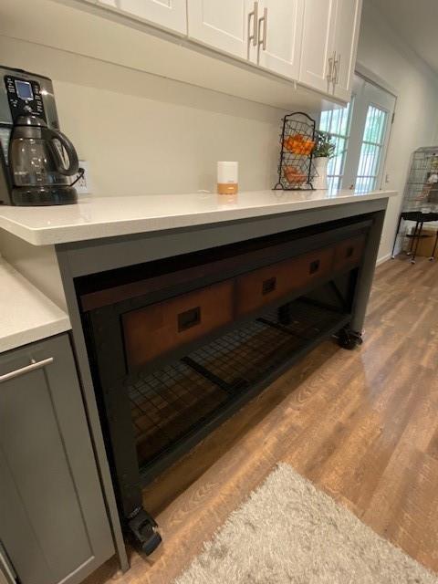 room details featuring white cabinets, light countertops, and wood finished floors