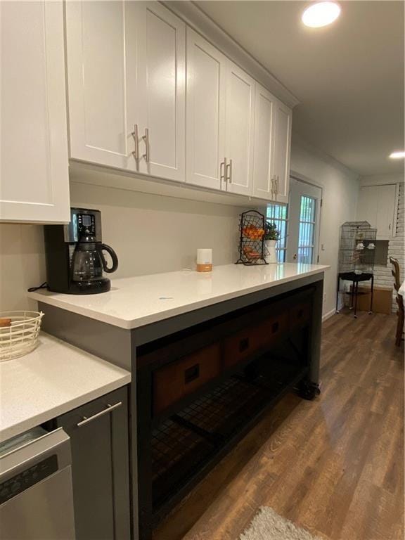 kitchen with dark wood-type flooring, light countertops, white cabinetry, stainless steel dishwasher, and recessed lighting