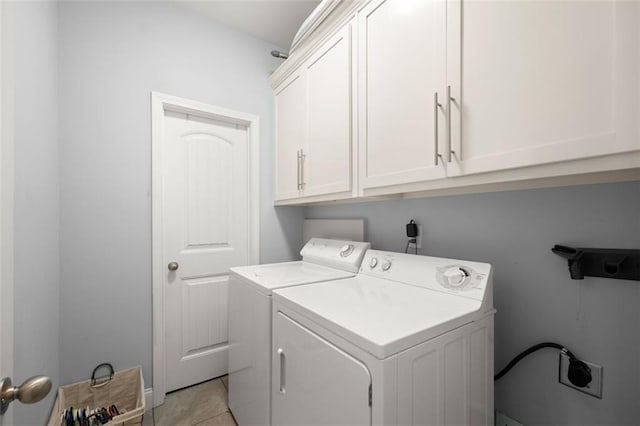 clothes washing area with cabinets, light tile patterned floors, and washing machine and clothes dryer