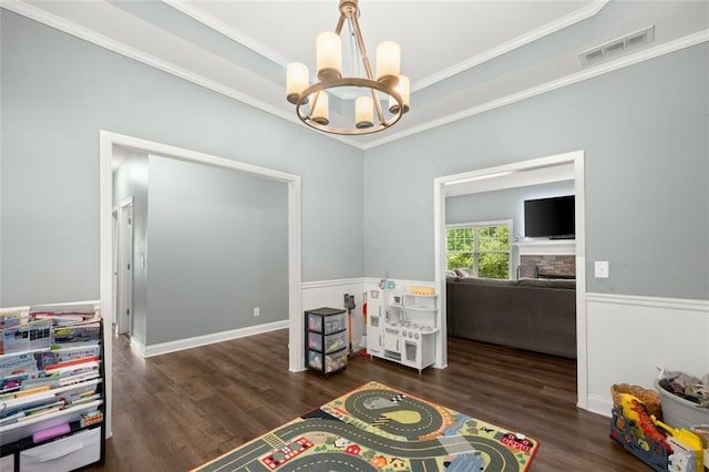 rec room featuring a fireplace, ornamental molding, dark wood-type flooring, and a chandelier