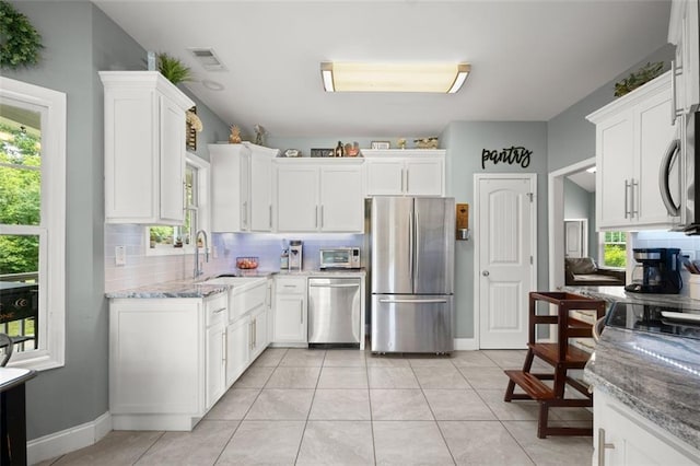 kitchen with backsplash, white cabinetry, light tile patterned floors, and appliances with stainless steel finishes