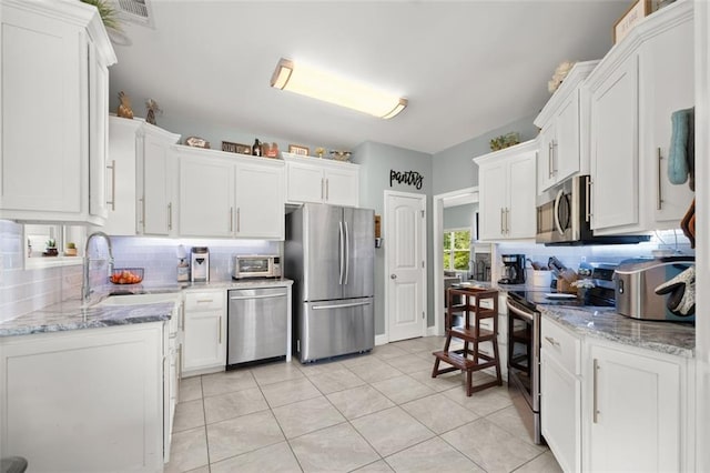 kitchen featuring appliances with stainless steel finishes, backsplash, white cabinetry, and sink