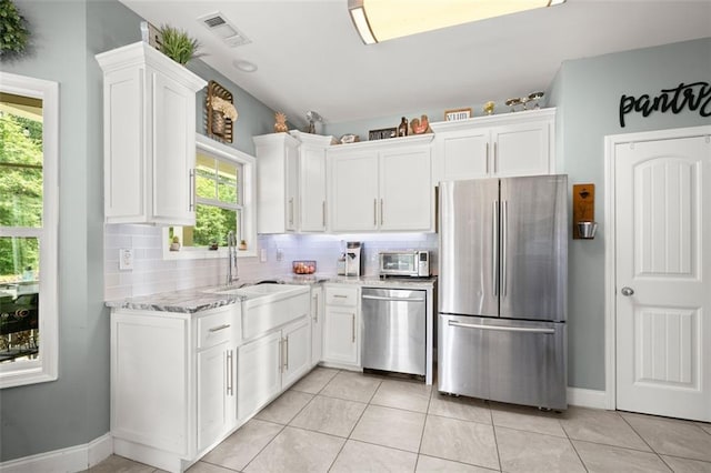 kitchen with light tile patterned floors, tasteful backsplash, light stone counters, white cabinetry, and stainless steel appliances