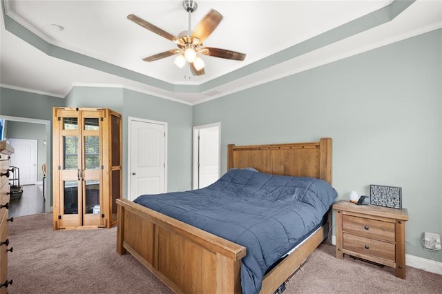 carpeted bedroom with ceiling fan, crown molding, and a tray ceiling