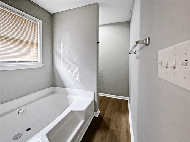 bathroom with a tub to relax in, hardwood / wood-style flooring, and a mail area