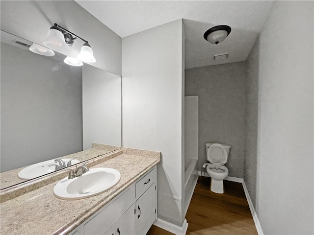 bathroom featuring hardwood / wood-style flooring, vanity, a shower, and toilet