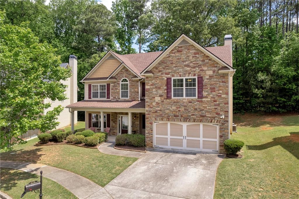 3178 Arbor Oaks Way, Snellville, GA 30039 - craftsman inspired home with an attached garage, stone siding, a front yard, a chimney, and driveway