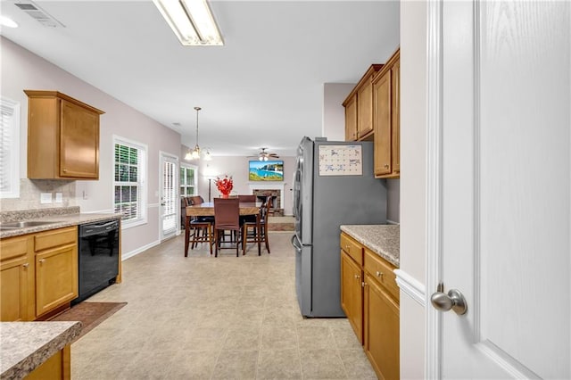 kitchen with decorative light fixtures, visible vents, a sink, freestanding refrigerator, and black dishwasher