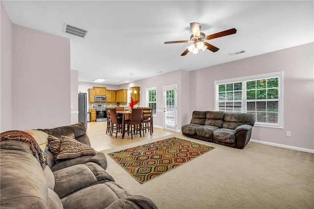living room with baseboards, ceiling fan, light carpet, and visible vents