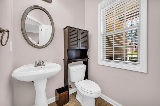 bathroom featuring toilet, baseboards, a sink, and tile patterned floors