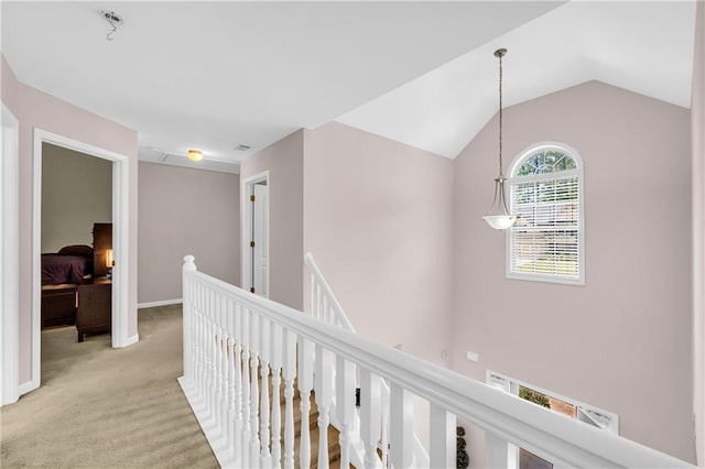 hallway with vaulted ceiling, light carpet, and an upstairs landing
