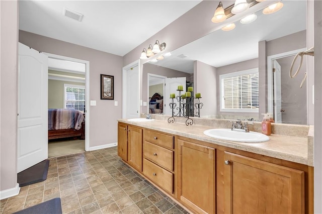 full bathroom with connected bathroom, double vanity, visible vents, and a sink