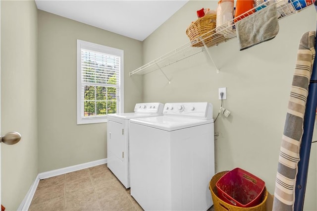 laundry area with washing machine and clothes dryer, light tile patterned floors, laundry area, and baseboards