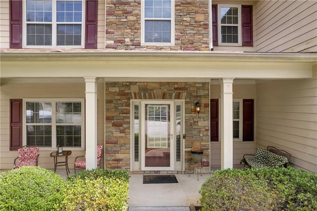 view of exterior entry featuring a porch and stone siding