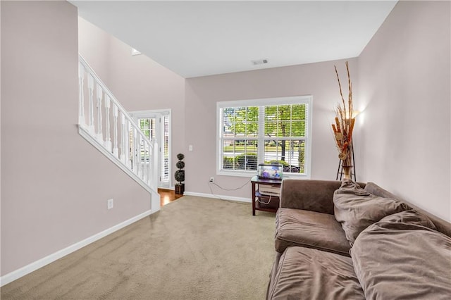 carpeted living area featuring stairs, baseboards, and visible vents