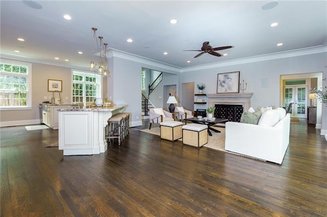 living room featuring dark wood-type flooring, ceiling fan, and crown molding