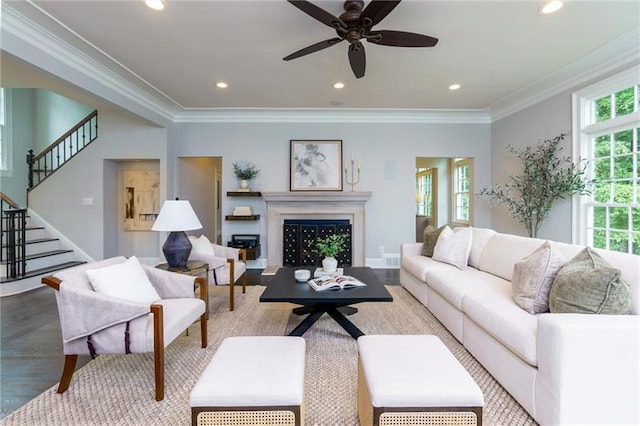 living room featuring ceiling fan, light wood-type flooring, and ornamental molding