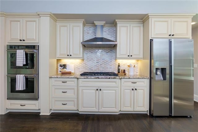 kitchen featuring backsplash, stainless steel appliances, light stone counters, and wall chimney exhaust hood