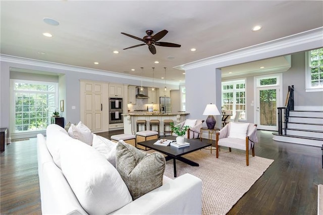 living room with dark wood-type flooring, crown molding, ceiling fan, and a healthy amount of sunlight