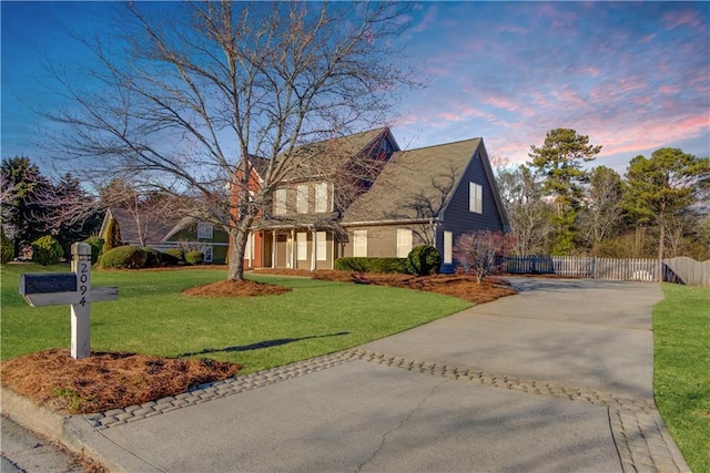 view of front of property with fence, a lawn, and concrete driveway