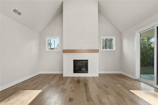 unfurnished living room featuring light hardwood / wood-style floors, lofted ceiling, and a fireplace