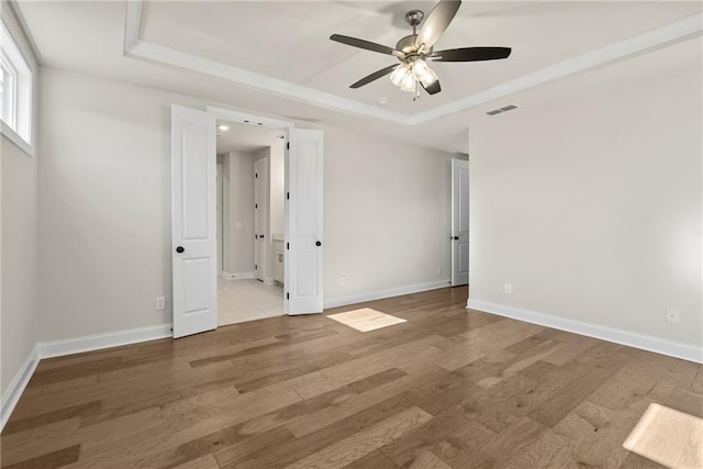 spare room with hardwood / wood-style floors, a raised ceiling, and ceiling fan