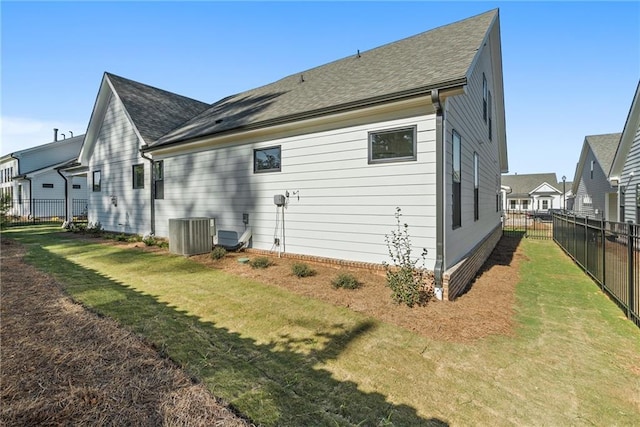 rear view of house featuring central AC and a lawn