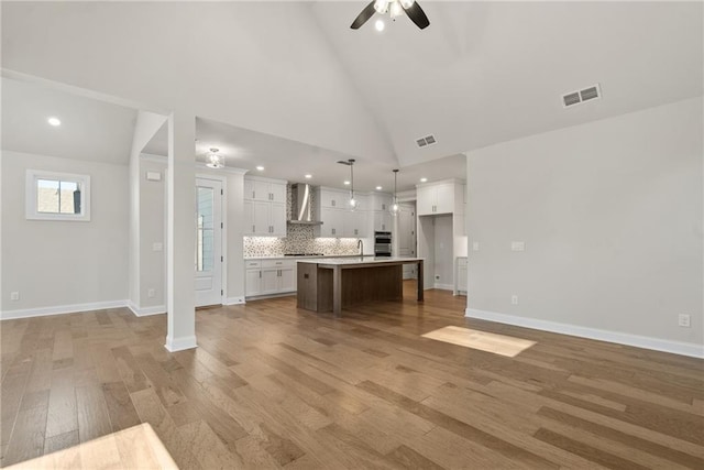 unfurnished living room featuring ceiling fan, sink, high vaulted ceiling, and light hardwood / wood-style flooring