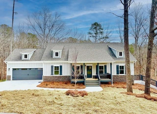 view of front of house featuring covered porch, a shingled roof, a garage, stone siding, and board and batten siding