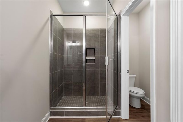 full bath with baseboards, wood finished floors, toilet, and a stall shower