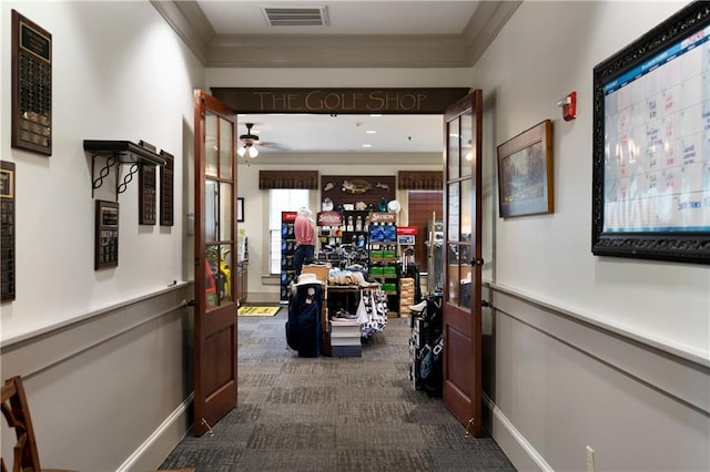 corridor with baseboards, visible vents, dark colored carpet, and ornamental molding