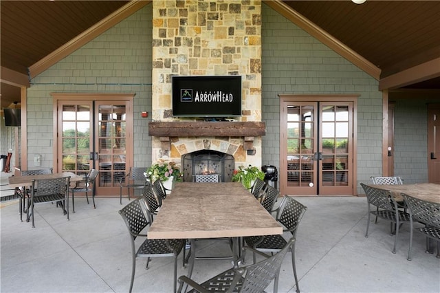 view of patio featuring outdoor dining area, french doors, and an outdoor stone fireplace