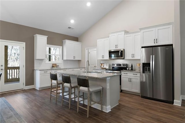 kitchen featuring visible vents, an island with sink, appliances with stainless steel finishes, white cabinetry, and a sink