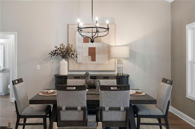 dining space featuring baseboards, an inviting chandelier, and wood finished floors