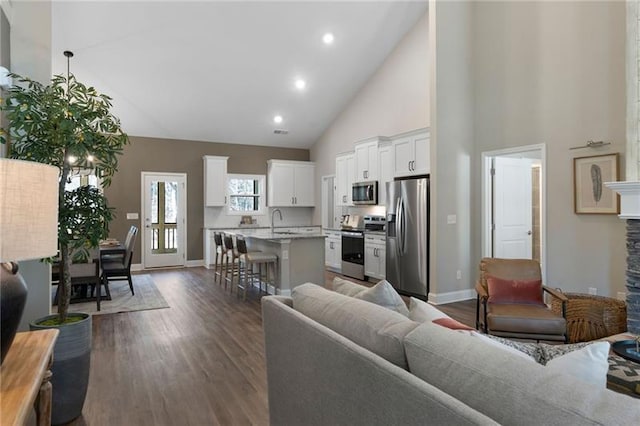 living area featuring dark wood-style floors, baseboards, high vaulted ceiling, a fireplace, and recessed lighting