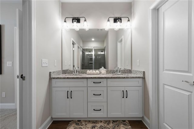 full bath featuring double vanity, a shower stall, baseboards, and a sink