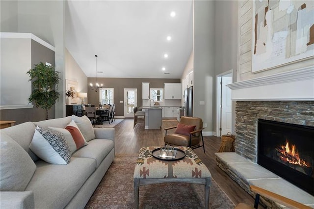 living room with baseboards, high vaulted ceiling, wood finished floors, and a fireplace